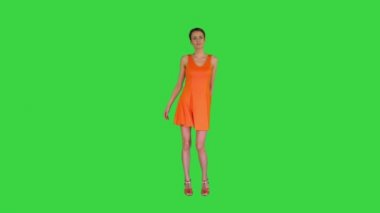 Yeşil Ekran 'da turuncu elbiseyle dans eden kısa saçlı güzel kadın, Chroma Key.