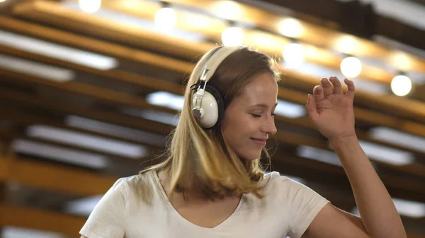 Csinos lány szőke hajjal zenét hallgat fejhallgatóval és tánccal. — Stock Fotó