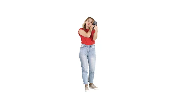Hermosa mujer joven usando rímel y mirando en su teléfono inteligente sobre fondo blanco. —  Fotos de Stock