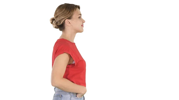 Young beautiful girl with hands in pockets walking on white background. — Stock Photo, Image