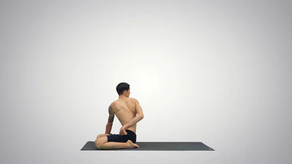 Un giovane uomo forte che fa esercizi di yoga allunga le gambe padmasana su sfondo sfumato. — Foto Stock