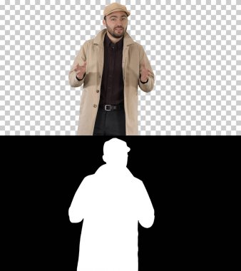 Trençkotlu yakışıklı adam Alpha Channel 'da yürüyor ve kamerayla konuşuyor.