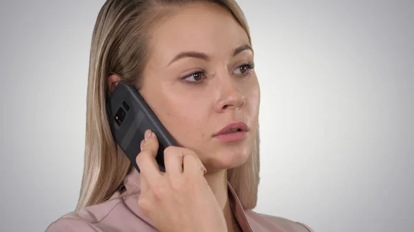 Face of young cheerful businesswoman talking on mobile phone on gradient background. — Stock Photo, Image