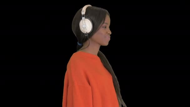 Sorridente donna afroamericana con le cuffie che cammina ascoltando la musica, Alpha Channel — Video Stock