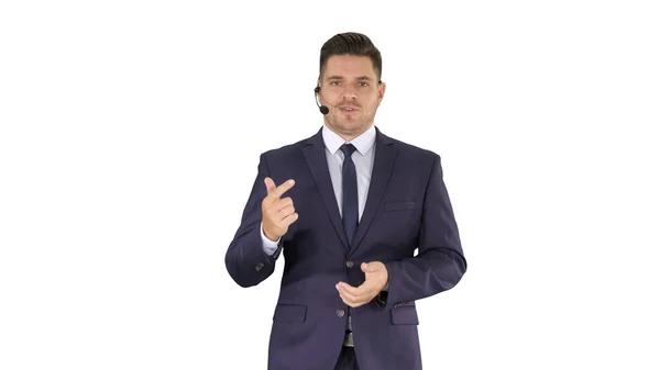 Handsome customer service center operator wearing a headset walking and talking to camera on white background. — Stock Photo, Image