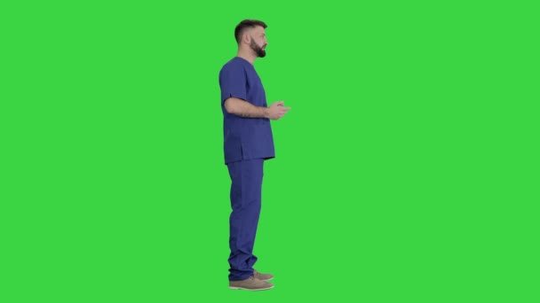 Männlicher Arzt in Uniform, der auf einem Green Screen etwas erklärt, Chroma Key. — Stockvideo