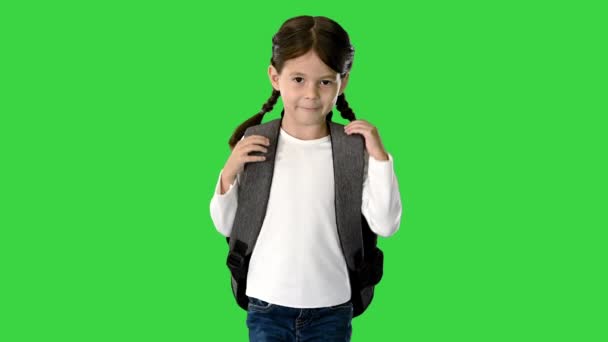 Lächelndes kleines Mädchen, das mit ihrem Rucksack zur Schule läuft und auf einem Green Screen in die Kamera schaut, Chroma Key. — Stockvideo