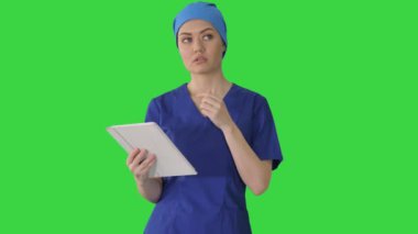 Yeşil Ekran, Krom Anahtar 'da yürürken dokunmatik ekran bilgisayar kullanan önlüklü genç kadın doktor veya hemşire..