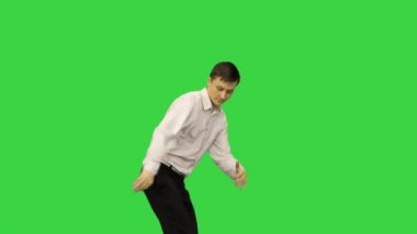 Beyaz gömlekli ve siyah pantolonlu genç adam yeşil ekranda break dans yapıyor, Chroma Key.