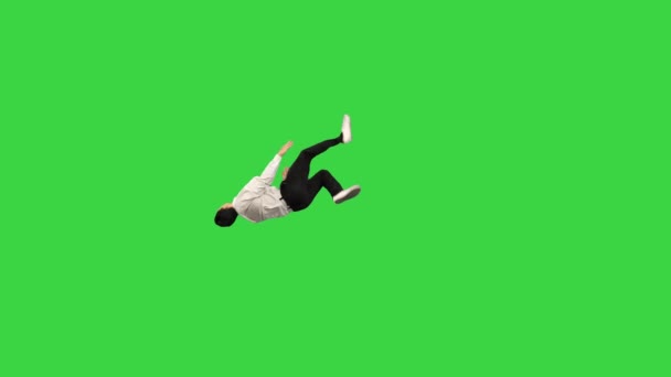 Beyaz gömlekli genç adam ters takla atıyor kameraya bakıyor ve yeşil ekranda yürüyor, Chroma Key. — Stok video