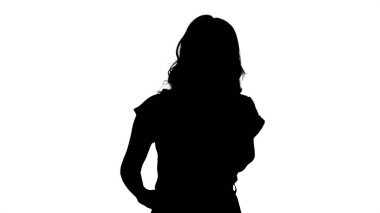 Siluet Genç kadın yürürken cep telefonuyla konuşuyor.