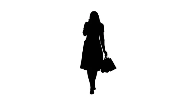 Silhouette Mujer joven de compras y hacer una llamada telefónica mientras camina. — Foto de Stock