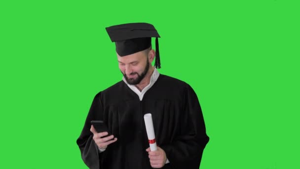 Graduate student sms 'en op de telefoon op een groen scherm, Chroma Key. — Stockvideo