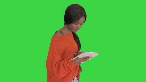 Sonriente mujer afroamericana usando tableta PC mientras camina en una pantalla verde, Chroma Key. — Vídeo de stock
