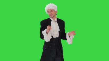 Eski moda cüppeli ve beyaz peruklu bir adam ellerini sallayarak Yeşil Ekran, Chroma Key 'de kameraya bakıyor..