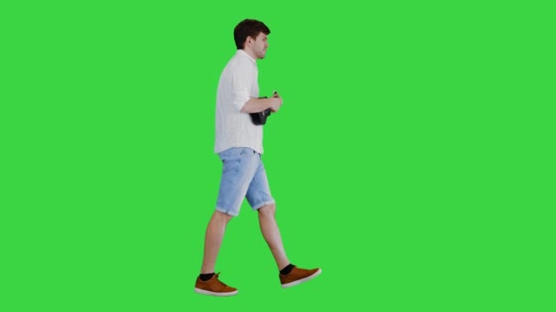 緑の画面、クロマキーの上を歩いている間、若い男はウクレレを演奏. — ストック動画