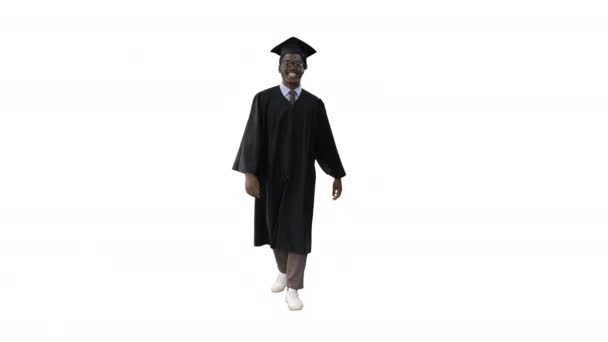 Glimlachende Afrikaanse Amerikaanse man student in afstuderen badjas lopen op witte achtergrond. — Stockvideo