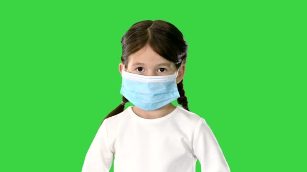 Маленька дівчинка знімає маску обличчя і посміхається перед камерою на зеленому екрані, Chroma Key. — стокове відео