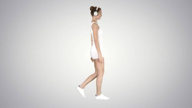 Gradyan gömlekli kadın kulaklık kullanarak müzik dinliyor ve arka planda yürüyor..