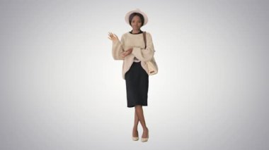 Örgü ve beyaz şapkalı genç Afro-Amerikan kadın. Grafik arka planda konuşup el kol hareketi yapıyor..