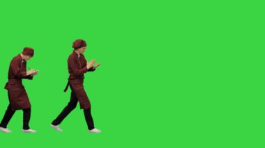 Kırmızı üniformalı iki komik aşçı, patronluk taslayan aşçının yeşil ekran Chroma Key 'e yemek tarifleri yazmasını takip ediyor..