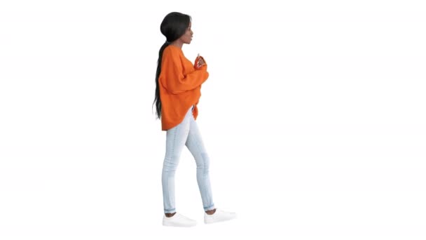 Mulher afro-americana alegre vestindo camisola brilhante e jeans conversando com a câmera no fundo branco. — Vídeo de Stock