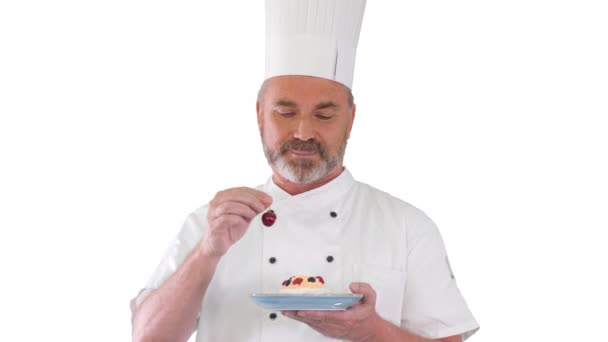 Chef mettre cerise sur le gâteau avant de le servir glaçage sur le gâteau sur fond blanc. — Video