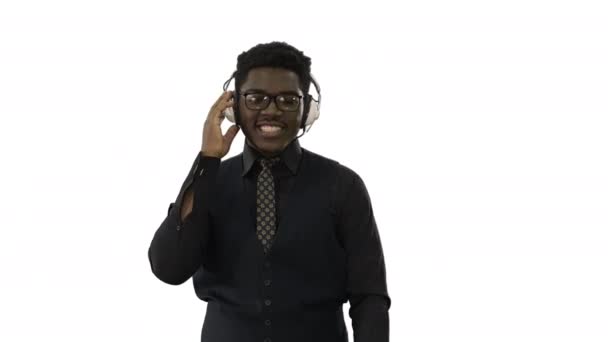 Smiling african american man in headphones grooving to music while walking and looking at camera on white background. — Stock Video