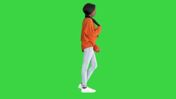 Femeia afro-americană zâmbitoare îmbrăcată în pulover strălucitor și blugi pozând cu mâinile în buzunare pe un ecran verde, Chroma Key . — Videoclip de stoc
