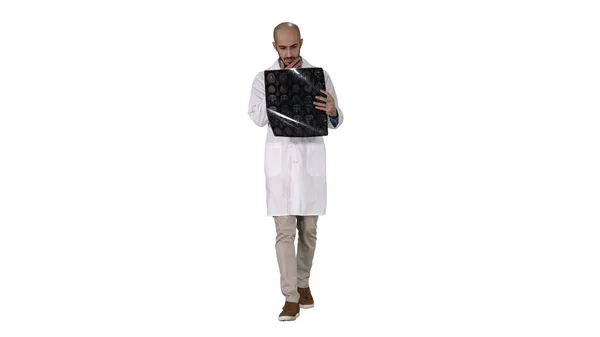 Medico arabo che esamina una risonanza magnetica cerebrale mentre cammina su sfondo bianco. — Foto Stock