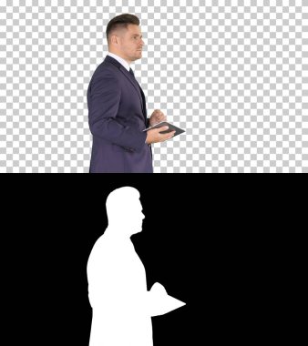 Genç ve zarif iş adamı yürürken PC tabletini kullanıyor, Alp.