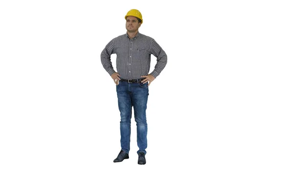 Smiling construction worker in yellow helmet looking at perfect well built object Hands on hips on white background. — Stock Photo, Image