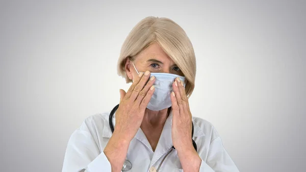 Oudere vrouw met een medisch masker met stethoscoop op gradiënt b — Stockfoto