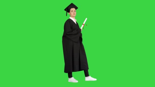 Estudante do sexo feminino em roupão de graduação segurando diploma e renunciando-o em torno de uma tela verde, Chroma Key. — Vídeo de Stock