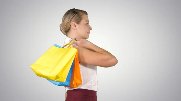 Joven mujer feliz con bolsas de compras caminando en gradiente backgro —  Fotos de Stock