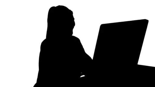 Silhouette Glückliche Frau bei einem Videoanruf vor ihrem Computer sitzend. — Stockfoto