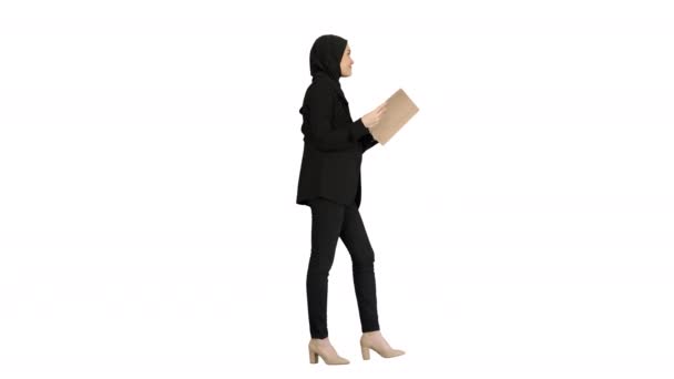 Empresaria musulmana sorprendida leyendo diario de negocios y agitando la cabeza mientras camina sobre fondo blanco. — Vídeos de Stock