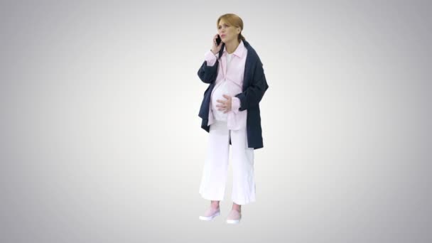 Pregnant woman with contractions feeling pain calling ambulance with cell phone on gradient background. — Stock Video