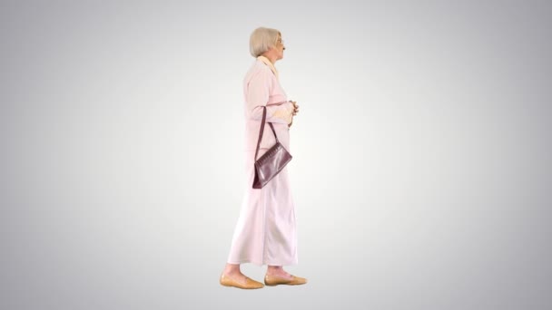 Привлекательная умная пожилая женщина ходит на градиентном фоне. — стоковое видео