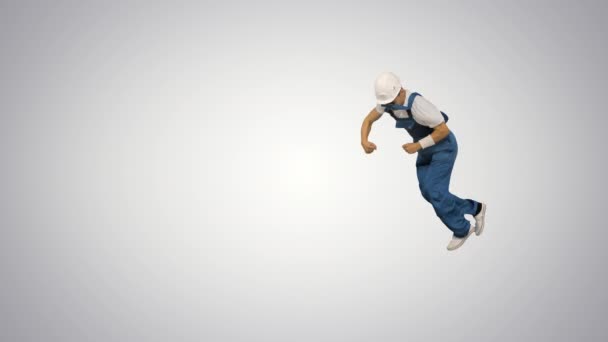 Mladý stavební pracovník ve žluté hardhat dělá ruční otáčení při pohledu na kameru a odchází na gradient pozadí. — Stock video