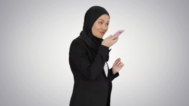 Chica musulmana en hijab usando smartphone para enviar mensajes de voz en un fondo degradado. — Vídeos de Stock