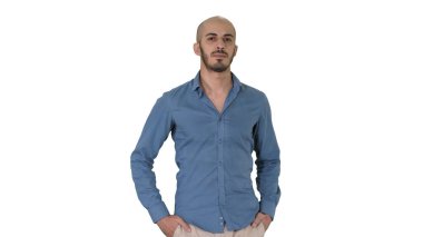 Yakışıklı, genç, sıradan kıyafetler giyen, elini cebine atan, beyaz arka planda gezen Arap bir adam..