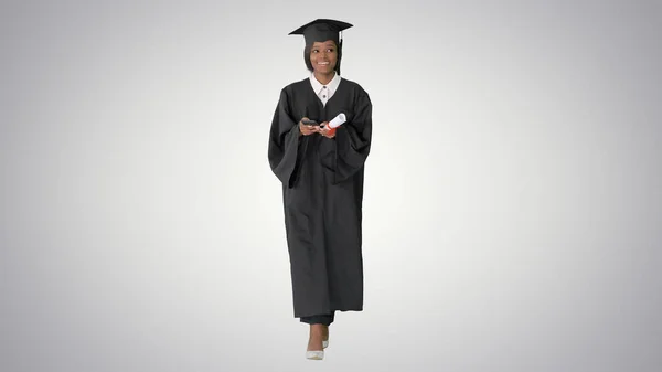 Sorridente afroamericana laureata con diploma texting on — Foto Stock