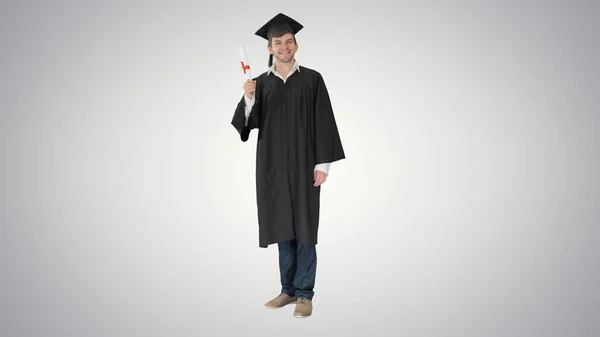 Happy male student in graduation robe posing and waiving with hi — Stock Photo, Image