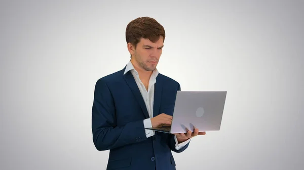 Jovem empresário concentrado trabalhando no laptop em pé — Fotografia de Stock