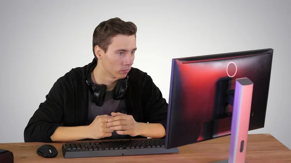 Poważny gracz siedzi przy komputerze i ogląda mecz na gradientowej ba — Zdjęcie stockowe