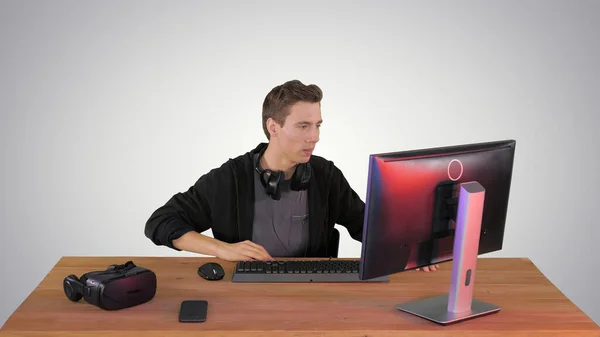 Nervous man watching video games on a PC computer on gradient ba