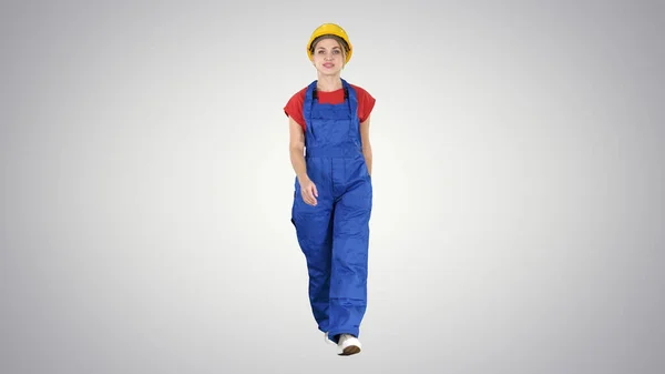 Mujer joven en hardhat amarillo caminando sobre fondo degradado. — Foto de Stock