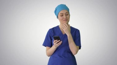 Düz bir arkaplanda akıllı telefonunu kullanan bir kadın doktor..