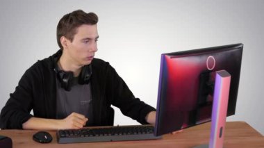 Gergin adam gradyan arka planda bilgisayar üzerinden video oyunları izliyor..